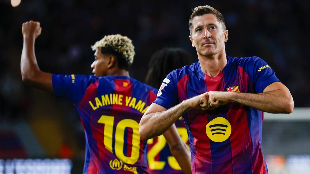 Piłkarz Robert Lewandowski świętuje bramkę, gestykulując do publiczności. W tle widać innego zawodnika z numerem 10 na koszulce.