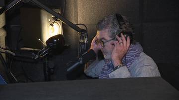 Starszy mężczyzna w studiu nagraniowym zakłada słuchawki.