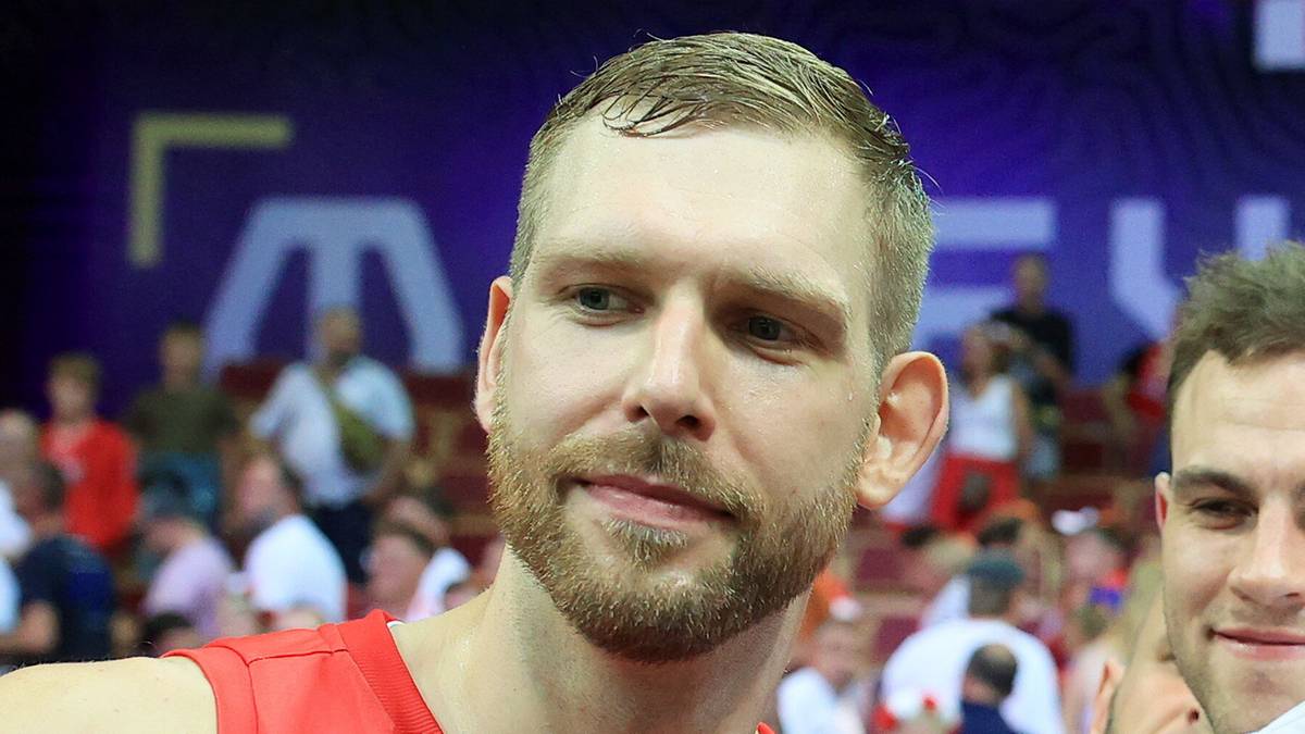 Trzech mężczyzn w strojach sportowych, dwóch w czerwonych z napisem POLSKA, jeden w białej koszulce pomiędzy nimi.