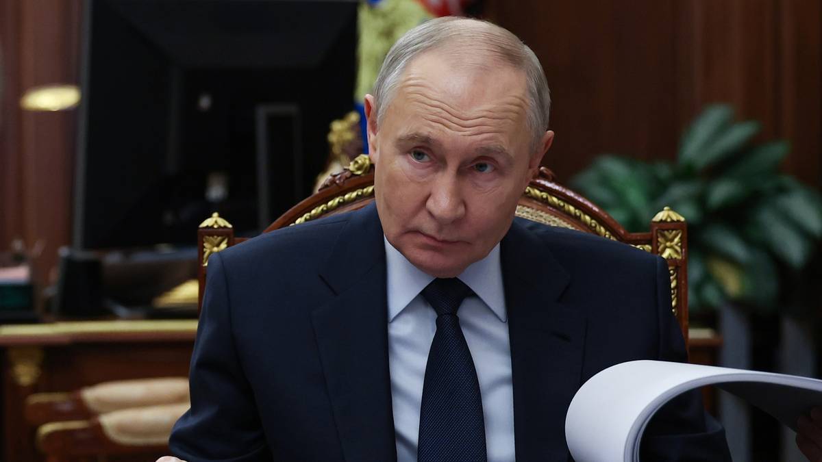 Vladimir Putin siedzący przy biurku z dokumentami