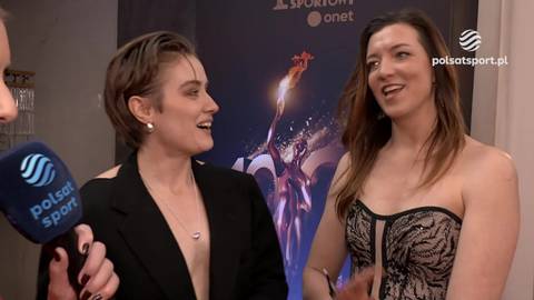 Dwie kobiety, jedna z kr&oacute;tkimi włosami w czarnej marynarce, druga z długimi włosami w gorsetowej sukience, rozmawiają ze sobą.