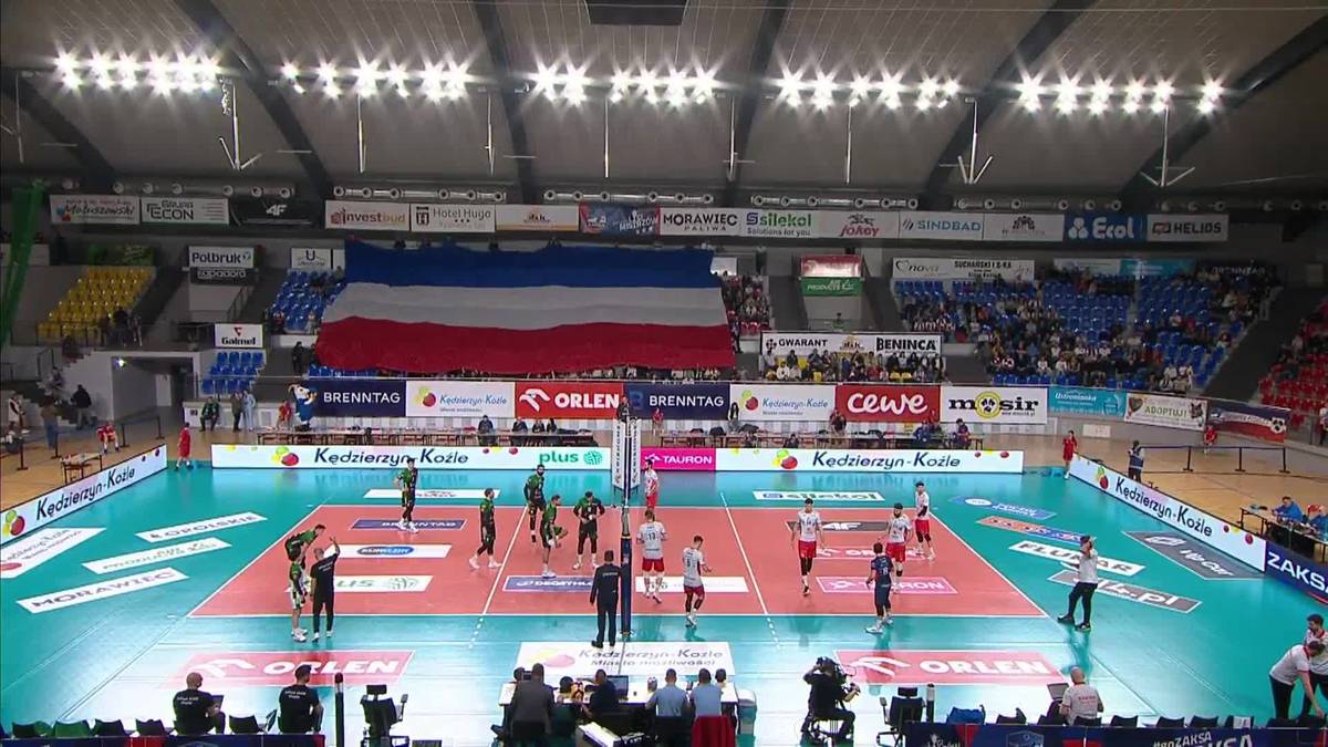 Boisko do siatk&oacute;wki z zawodnikami i trybunami.