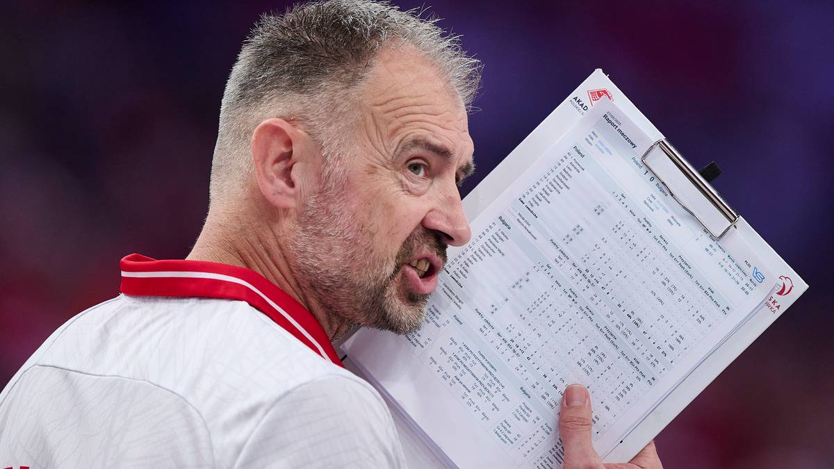 Trener siatkarskiej reprezentacji Polski z notesem w dłoni, skupiony i mówiący.