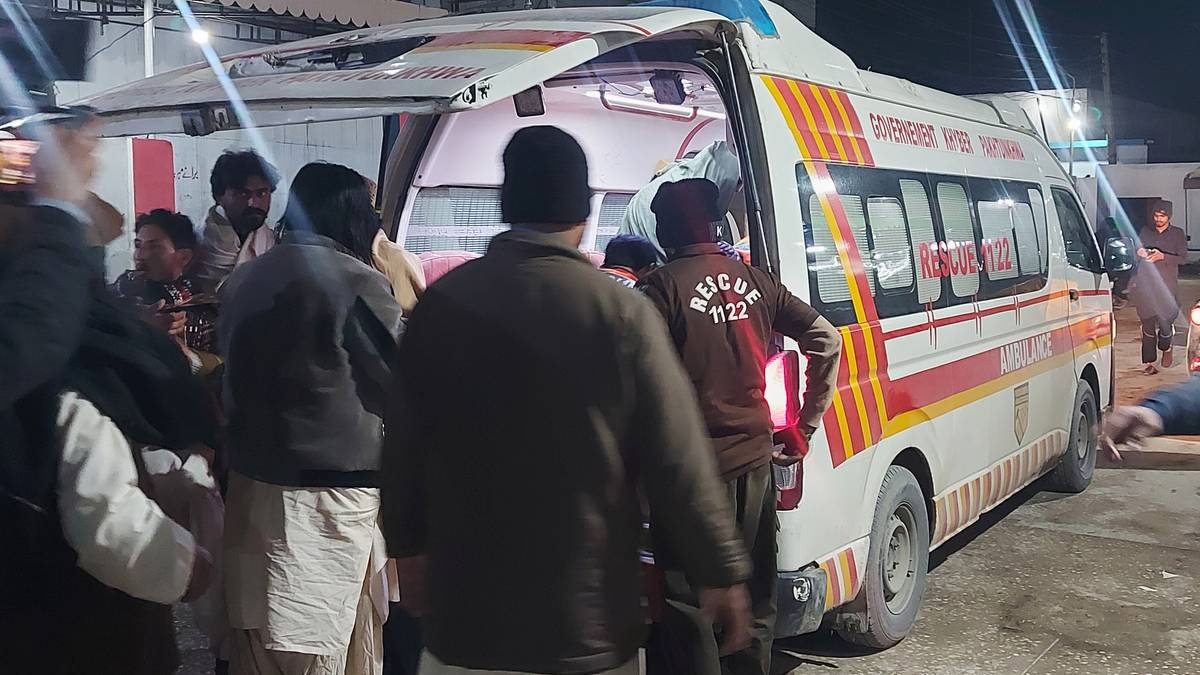 Osoby stoją wok&oacute;ł otwartej karetki pogotowia, z kt&oacute;rej wyciągany jest pacjent.