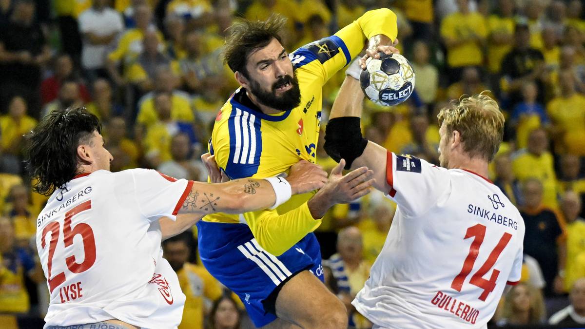 Gracz w żółtej koszulce z piłką ręczną w ręku próbuje rzucić do bramki, broniony przez dwóch graczy w białych koszulkach.