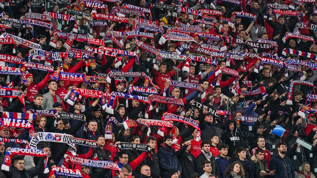 Tłum kibic&oacute;w na stadionie trzymających szale klubowe, wspierających swoją drużynę.