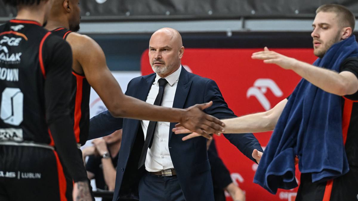 Trzej mężczyźni w strojach sportowych i garniturze podczas gry w koszykówkę.