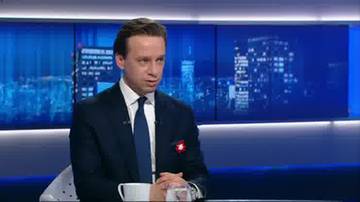 Krzysztof Bosak w garniturze siedzi w studiu telewizyjnym, w tle nocne miasto.