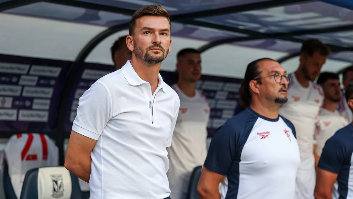 Dw&oacute;ch mężczyzn w strojach sportowych stoi obok siebie, patrząc w tym samym kierunku.