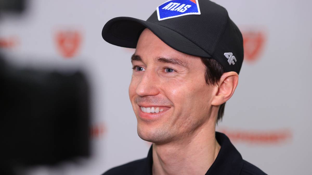 Uśmiechnięty Kamil Stoch w czapce z daszkiem i koszulce polo.