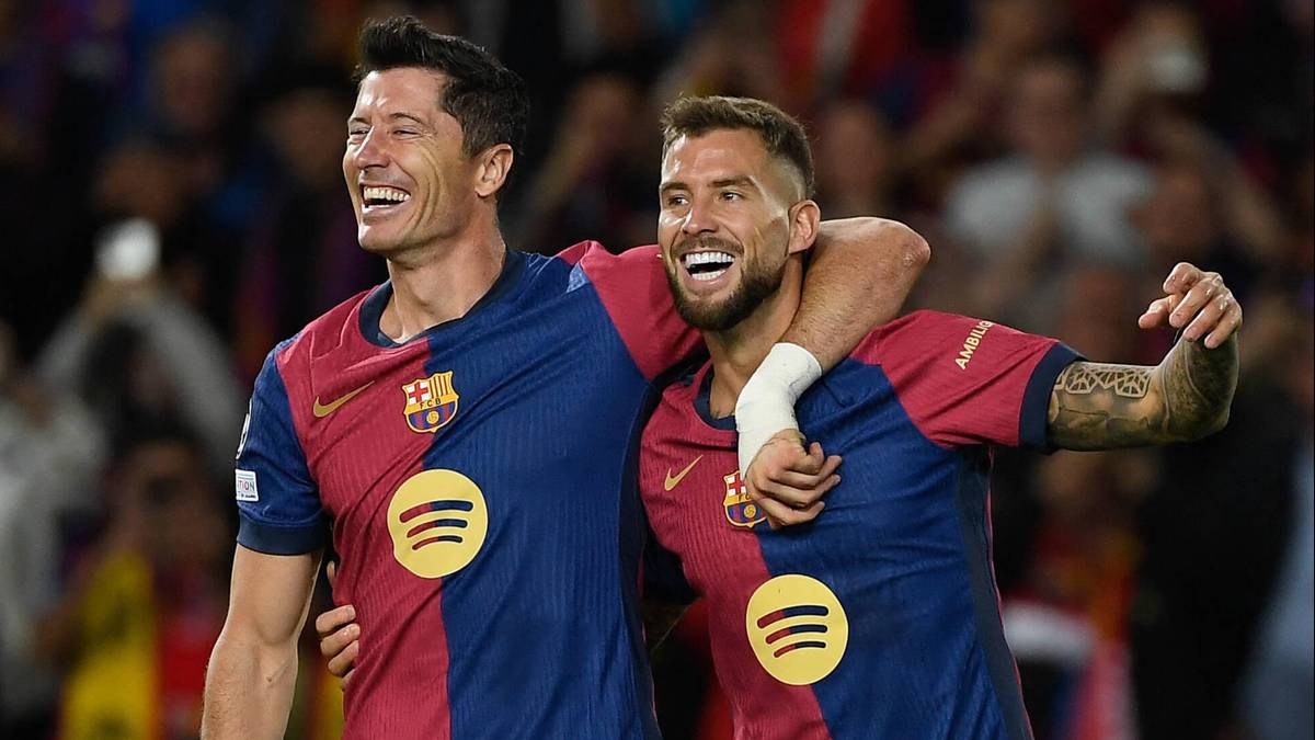 Dwóch piłkarzy FC Barcelony cieszy się podczas meczu, obejmując się ramionami i śmiejąc.