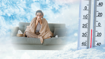 Kobieta siedzi na kanapie okryta kocem, wycierając nos chusteczką, obok leży laptop. Obok znajduje się termometr wskazujący niską temperaturę.