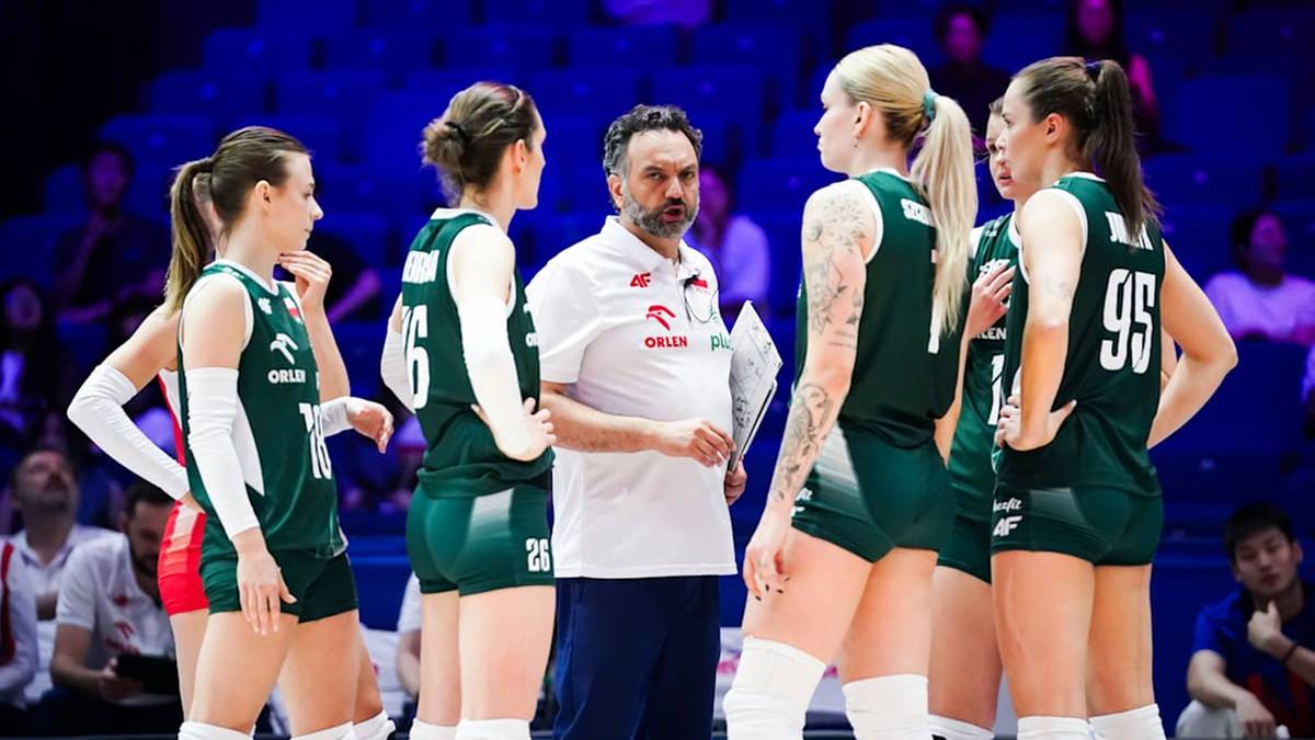 Drużyna siatkarek w zielonych strojach sportowych, otaczająca trenera w białej koszulce.