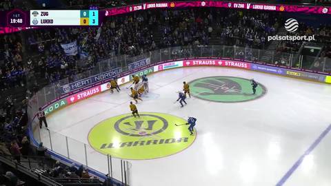 Hokeiści w niebieskich i ż&oacute;łtych strojach rywalizują na lodowisku podczas meczu. Na tablicy wynik&oacute;w widnieje wynik 0:1.