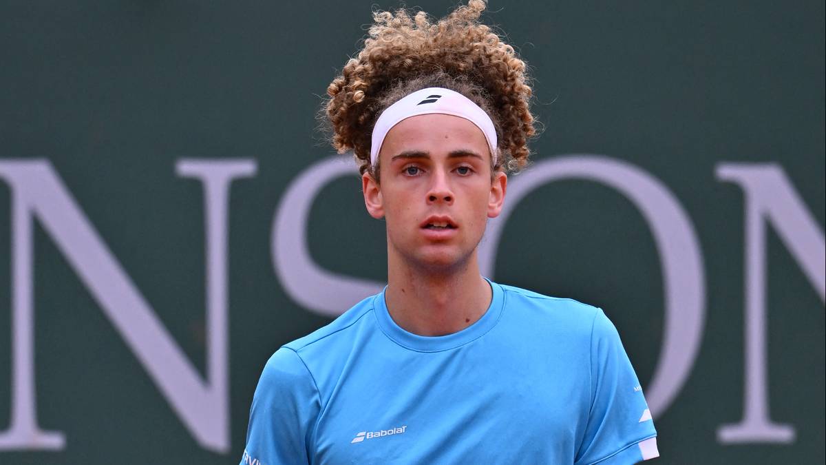 Młody tenisista w niebieskiej koszulce i białych spodenkach na korcie tenisowym