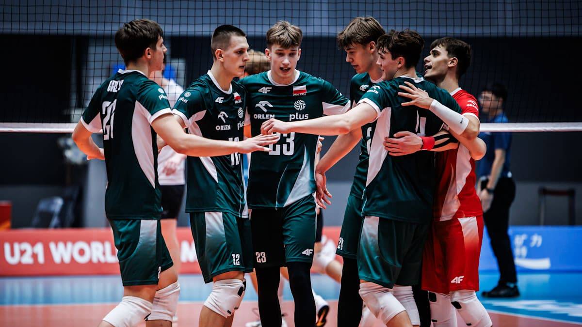 Siatkarze reprezentacji Polski mężczyzn w zielono-białych strojach po wygranym meczu, stojący w grupie i celebrujący zwycięstwo, z widoczną tablicą wyników w tle.