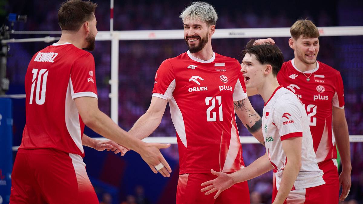 Siatkarze w czerwonych strojach świętują na boisku po meczu, ściskając sobie dłonie.