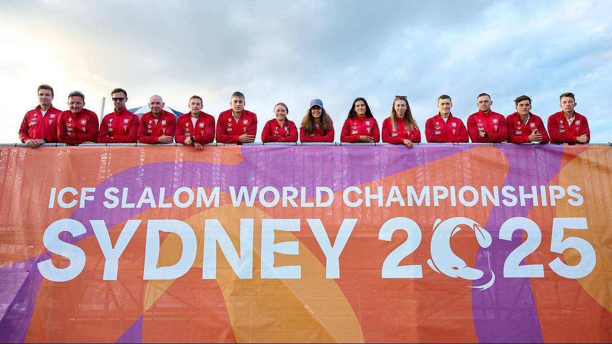 Grupa ludzi pozuje przed banerem "ICF SLALOM WORLD CHAMPIONSHIPS SYDNEY 2025".