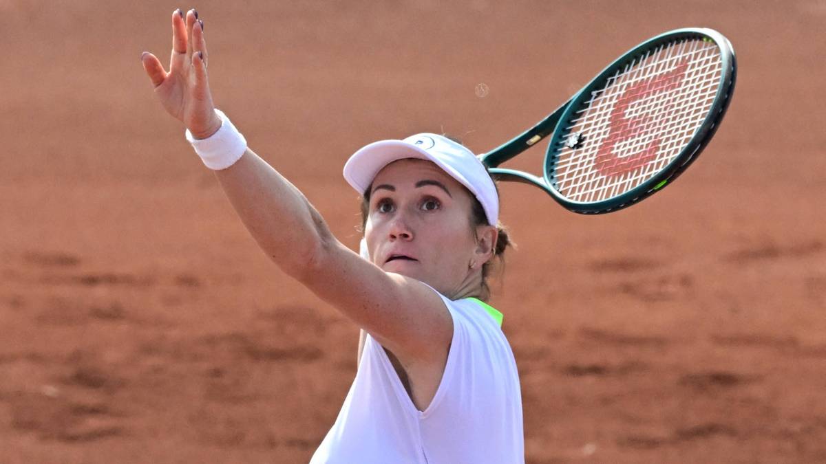 Tenisistka Katarzyna Kawa w białej koszulce i ż&oacute;łtej sp&oacute;dniczce wykonuje serwis podczas meczu na korcie ziemnym.