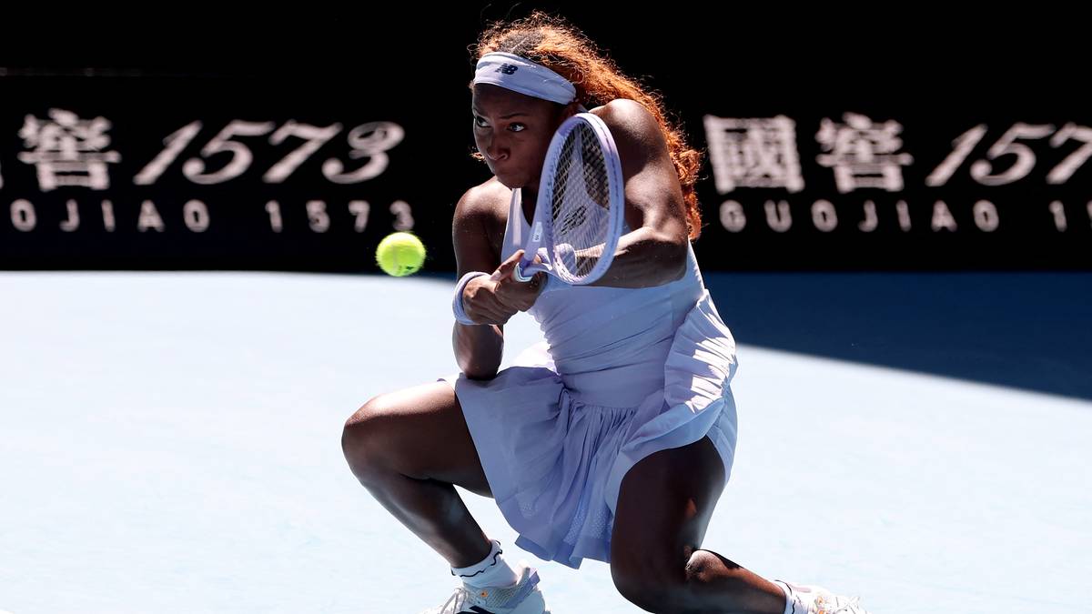 Tenisistka w białej sukience na korcie, wykonująca uderzenie forehand.