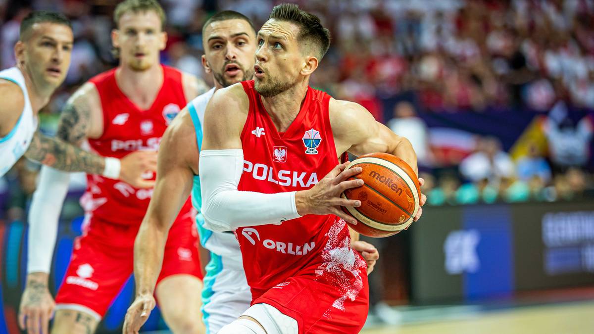 Koszykarz w czerwonej koszulce z napisem "POLSKA" trzyma piłkę podczas meczu.