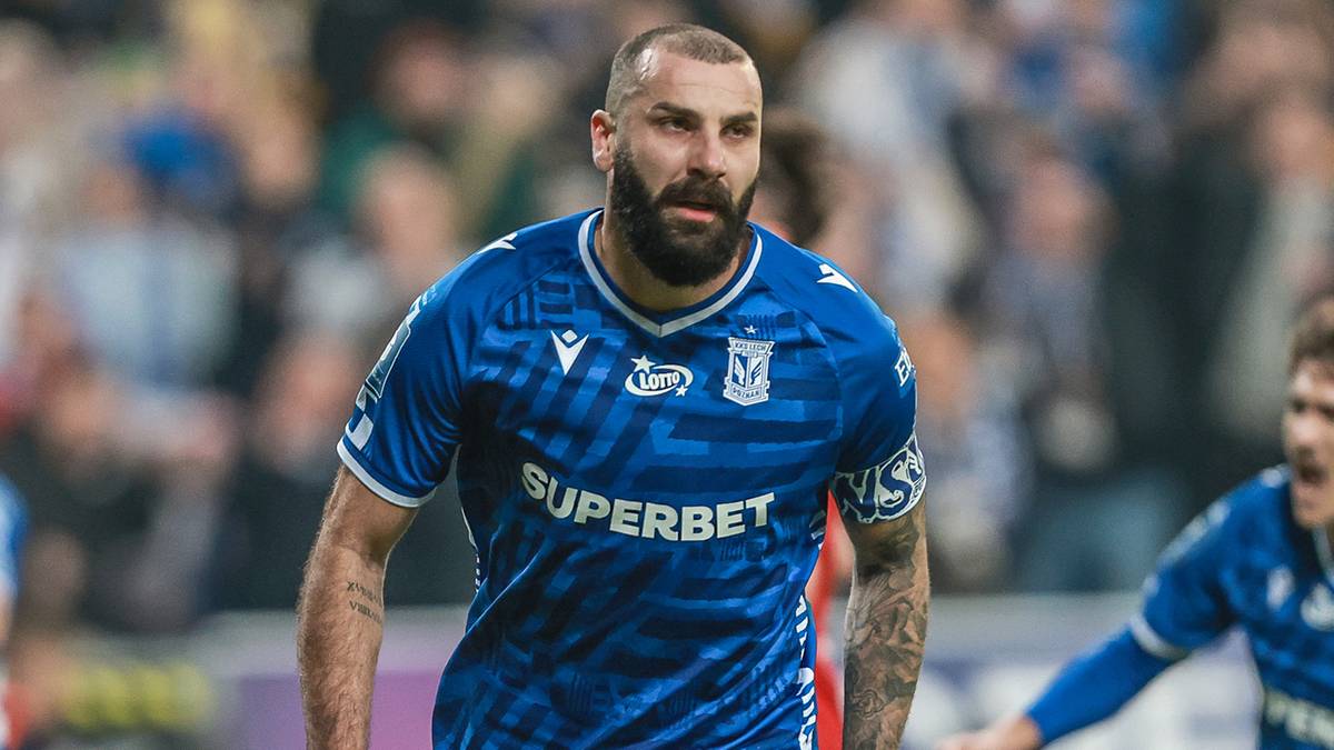 Mikael Ishak, napastnik Lecha Poznań, biegnie po boisku w niebieskiej koszulce podczas meczu.