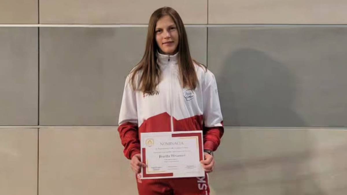 Jowita Wrzesień w stroju sportowym z napisem "POLSKA" trzyma certyfikat.