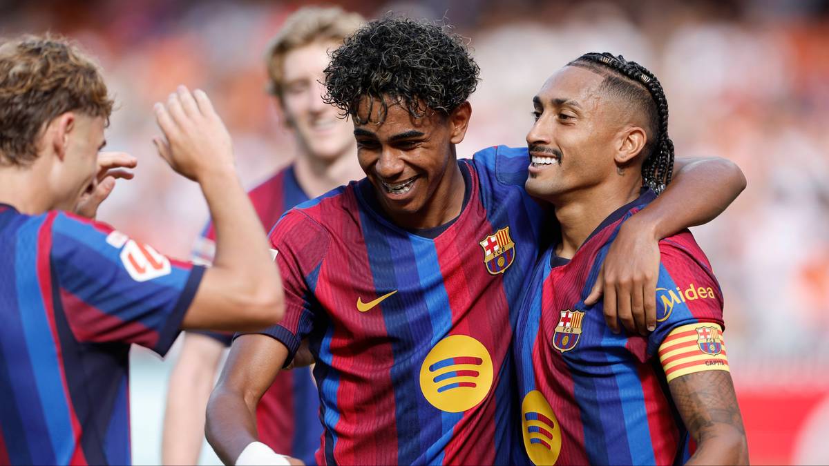 Dw&oacute;ch piłkarzy FC Barcelony w strojach z herbem klubu i logiem Spotify, radośnie obejmują się i uśmiechają. Jeden z nich ma rękę na ramieniu drugiego.