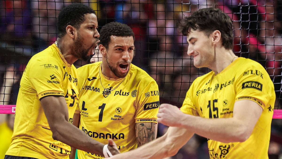 Trzech siatkarzy w ż&oacute;łtych strojach z czarnymi spodenkami, patrzących na siebie i rozmawiających podczas meczu.