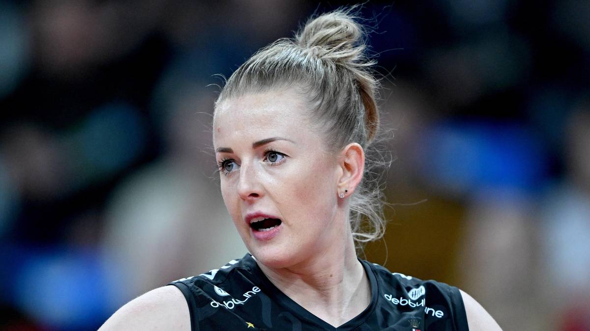 Portret siatkarki z blond włosami spiętymi w kok, w czarnej koszulce sportowej.