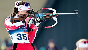 Biathlonistka celująca z karabinu podczas zawod&oacute;w, ubrana w biało-czerwony str&oacute;j sportowy z numerem 35.