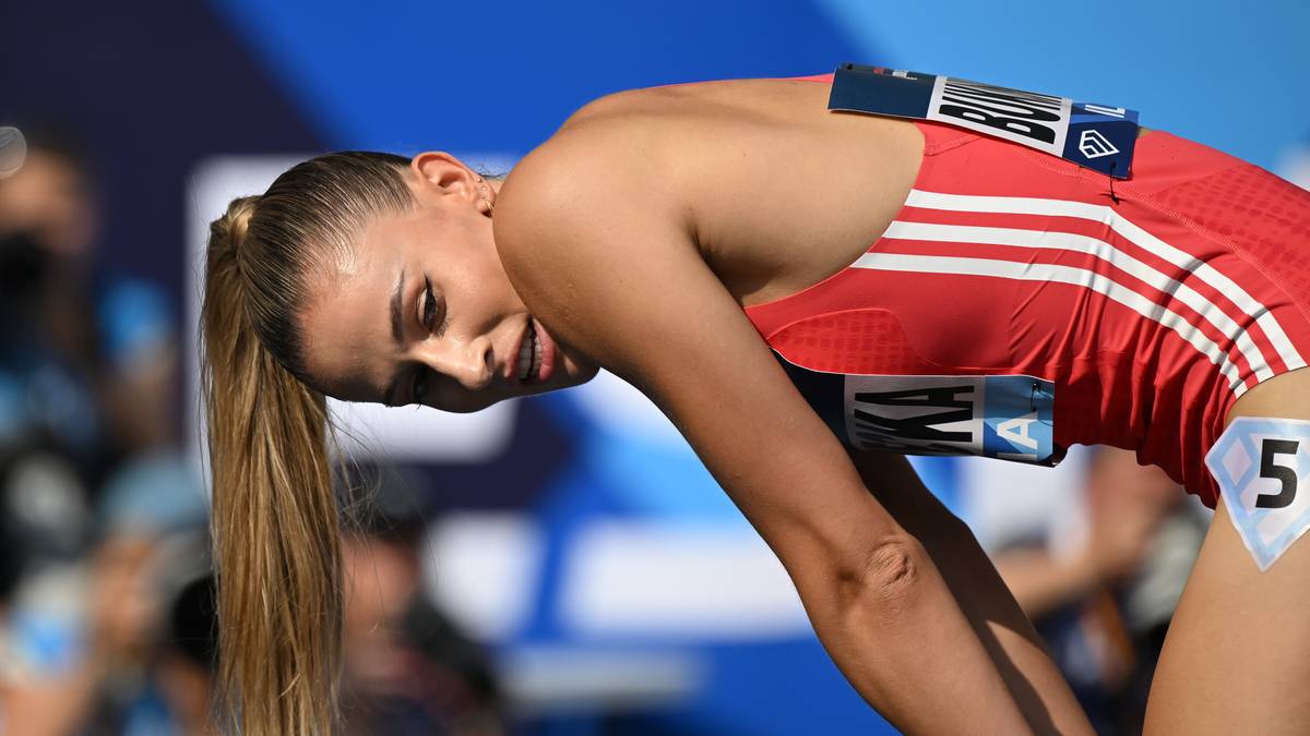 Atletka Natalia Bukowiecka w czerwonym stroju sportowym z białymi paskami, pochylona z wyrazem wysiłku na twarzy.