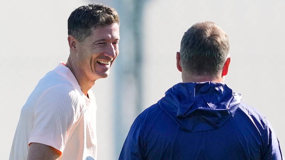 Robert Lewandowski rozmawia z trenerem i innym zawodnikiem na boisku.