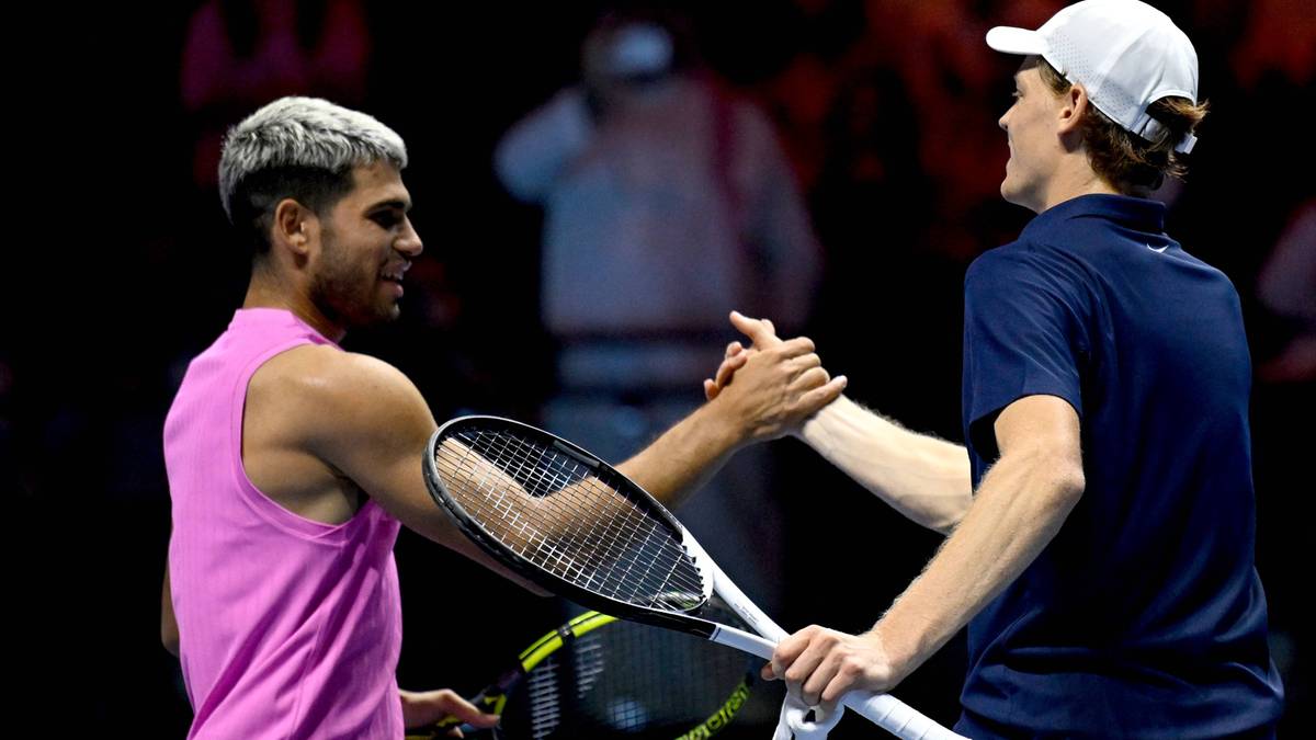 Dw&oacute;ch tenisist&oacute;w, Jannik Sinner i Carlos Alcaraz, ściska sobie dłonie po meczu, obaj trzymają rakiety tenisowe.