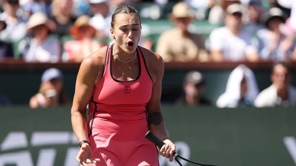 Tenisistka Aryna Sabalenka w r&oacute;żowej sukience sportowej krzyczy podczas meczu, trzymając rakietę tenisową.