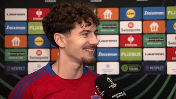 Karol Struski, piłkarz z krótkimi, kręconymi włosami, uśmiecha się do mikrofonu.