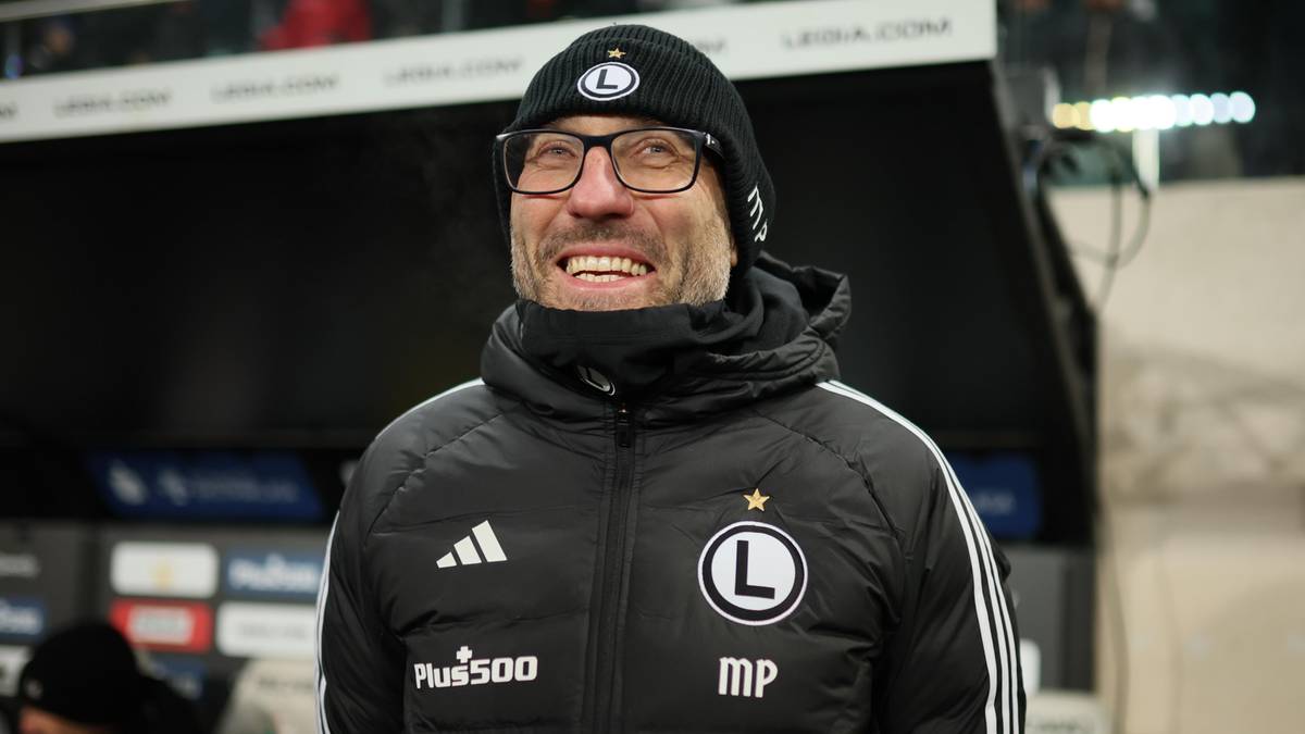 Portret trenera Marka Papszuna w czapce i okularach, z szerokim uśmiechem.