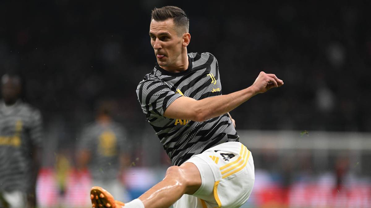 Arkadiusz Milik, piłkarz Juventusu, w akcji na boisku, w koszulce z czarno-szarymi pasami i białych spodenkach.