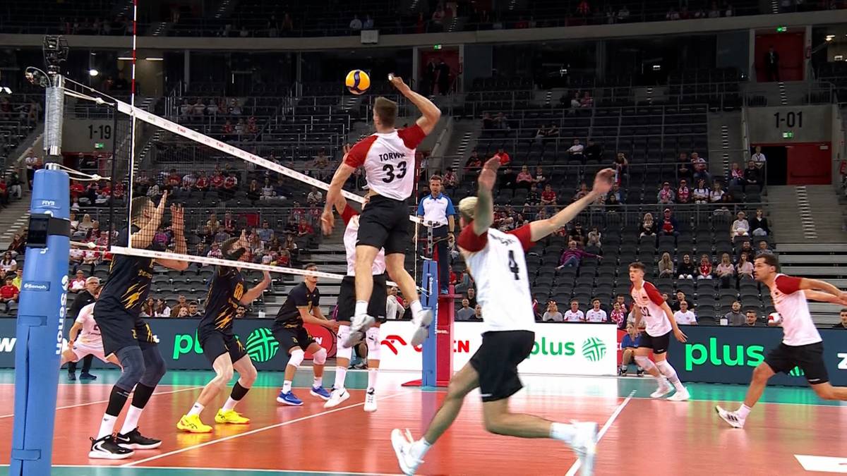 Mecz siatkówki pomiędzy Niemcami a Ukrainą, pokazujący akcję ataku ze strony zawodnika w białej koszulce.