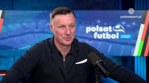 Tomasz Hajto, były polski piłkarz, siedzi przed mikrofonem i m&oacute;wi do kamery. W tle znajduje się ekran z logiem Polsat Futbol. Hajto ma na sobie ciemną bluzę.