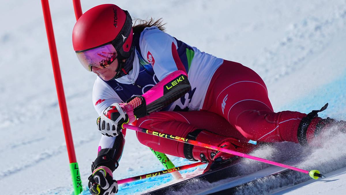 Narciarka alpejska Maryna w czerwonym kasku i stroju narciarskim podczas zjazdu na nartach.