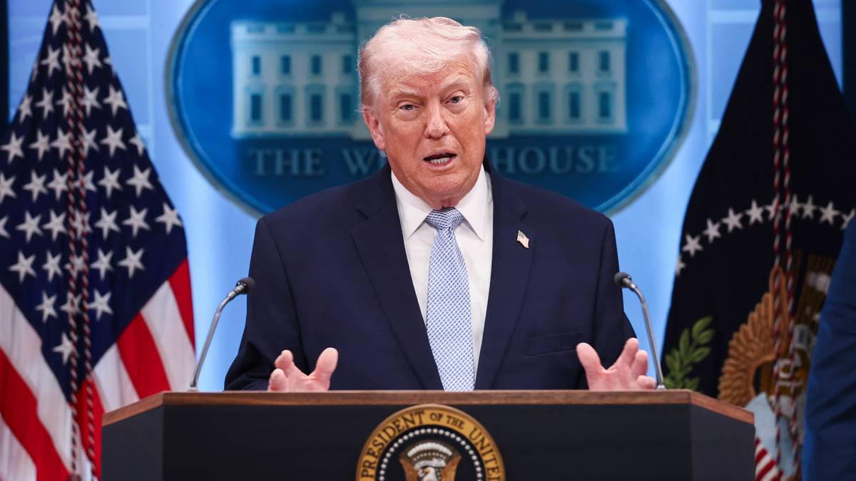 Donald Trump przemawia za m&oacute;wnicą z emblematem prezydenta USA, w tle flagi Stan&oacute;w Zjednoczonych i logo Białego Domu