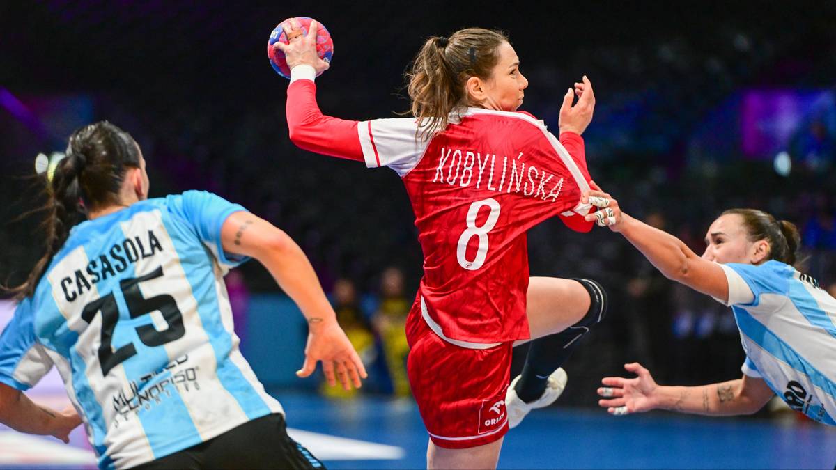 Piłkarka ręczna w czerwonej koszulce z numerem 8, Kobylińska, wykonuje rzut do bramki, podczas gdy dwie zawodniczki w niebieskich strojach próbują ją zablokować.