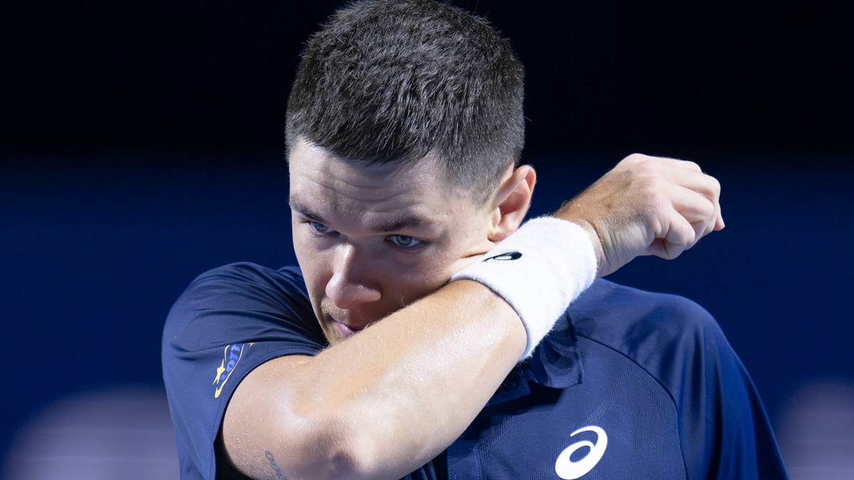 Tenisista Kamil Majchrzak wyciera pot z twarzy podczas meczu.