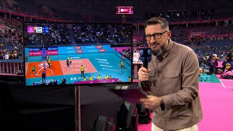 Jakub Bednaruk analizuje mecz siatk&oacute;wki między Bogdanka LUK Lublin a Indykpol AZS Olsztyn w TAURON Pucharze Polski, stojąc przed ekranem pokazującym boisko z zawodnikami.