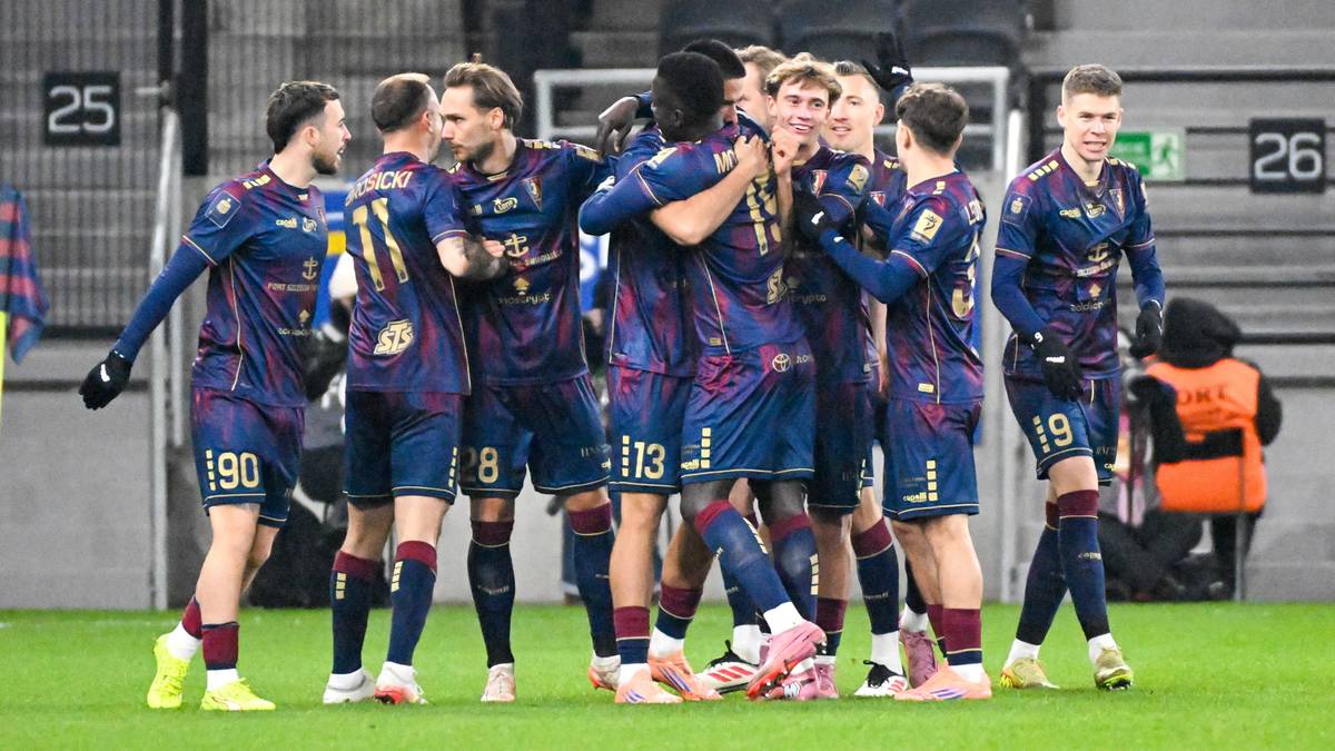 Drużyna piłkarska świętuje gola, przytulając się na boisku.