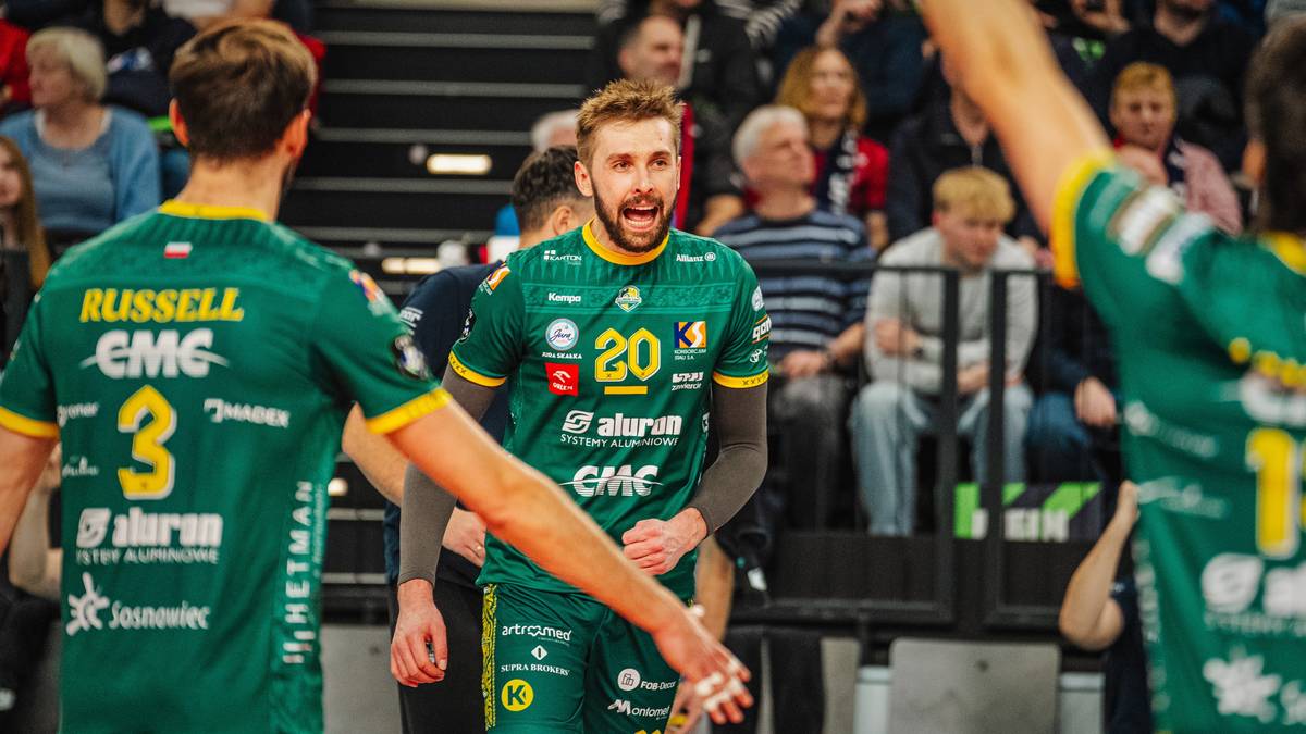 Trzech siatkarzy w zielonych strojach sportowych podczas meczu, jeden z nich wyraża silne emocje.