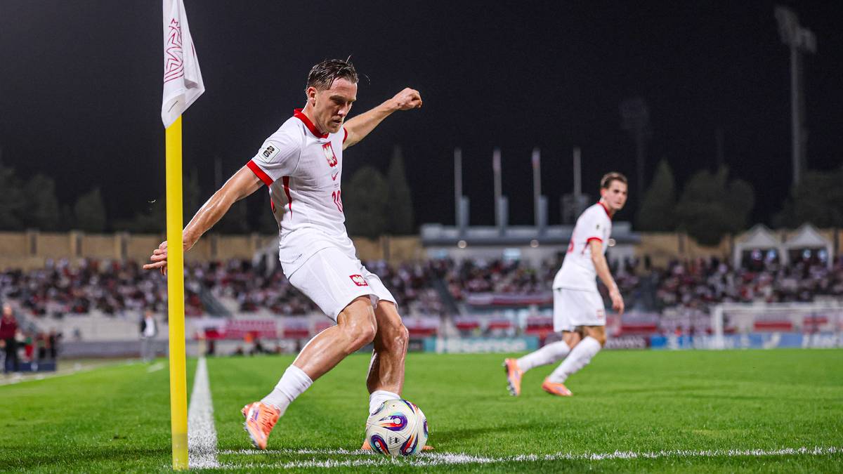 Piłkarz wykonuje rzut rożny na boisku piłkarskim.