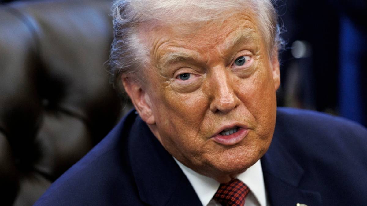 Donald Trump przemawia, ubrany w granatowy garnitur i czerwoną muszkę.