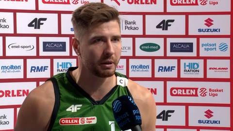 Michał Jankowski, koszykarz w zielonej koszulce z logo 4F, udziela wywiadu przed ścianą z logo Orlen.